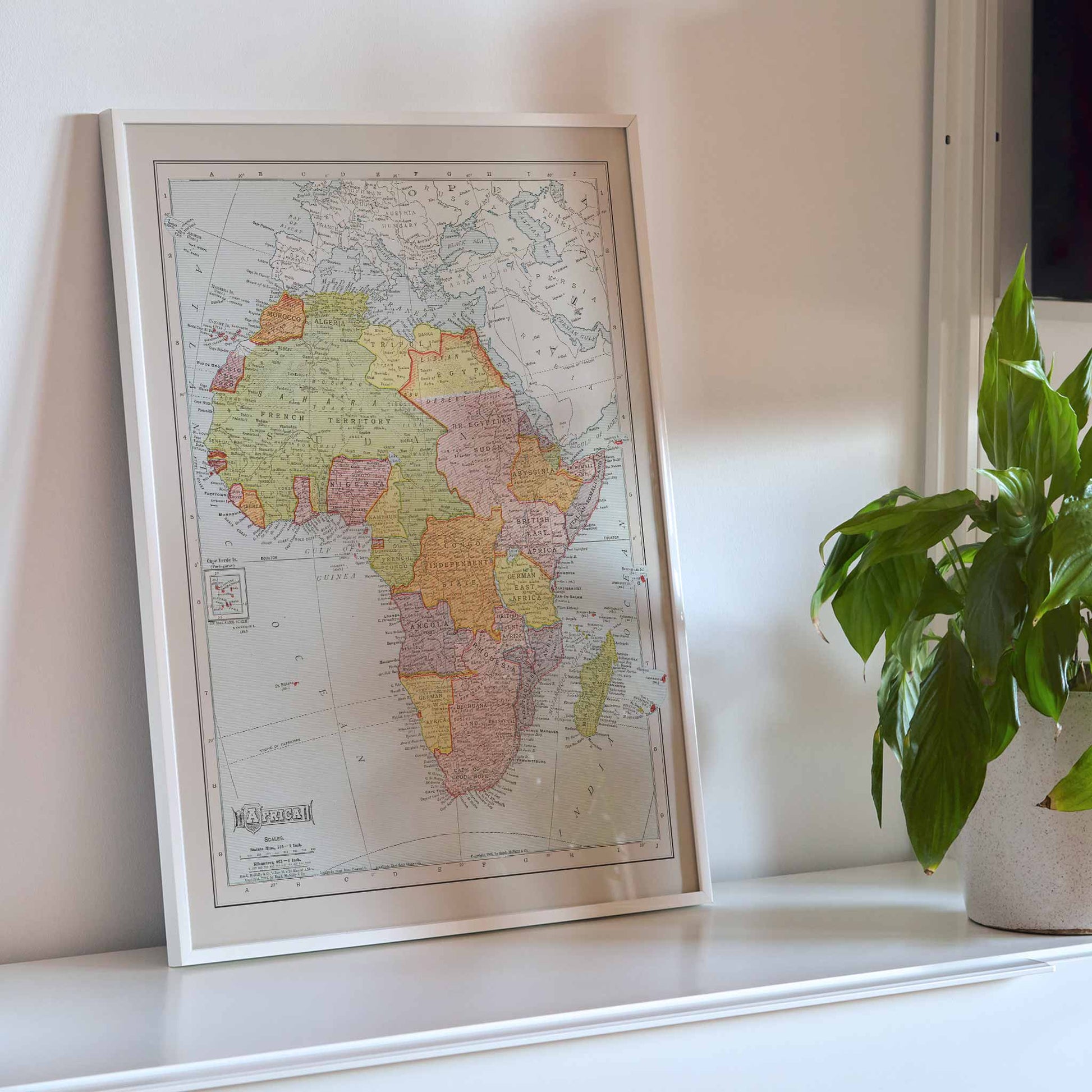 Rand McNally and Company Africa Map vintage poster of the African continent in muted green yellow pink and beige tones, framed and displayed in modern living room decor