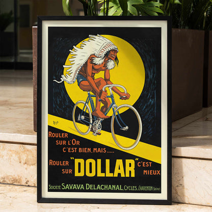 Michel Liebeaux Dollar Bicycles poster with advertising cyclist, white headdress, yellow circle, black background and bold orange lettering, framed and displayed in home decor