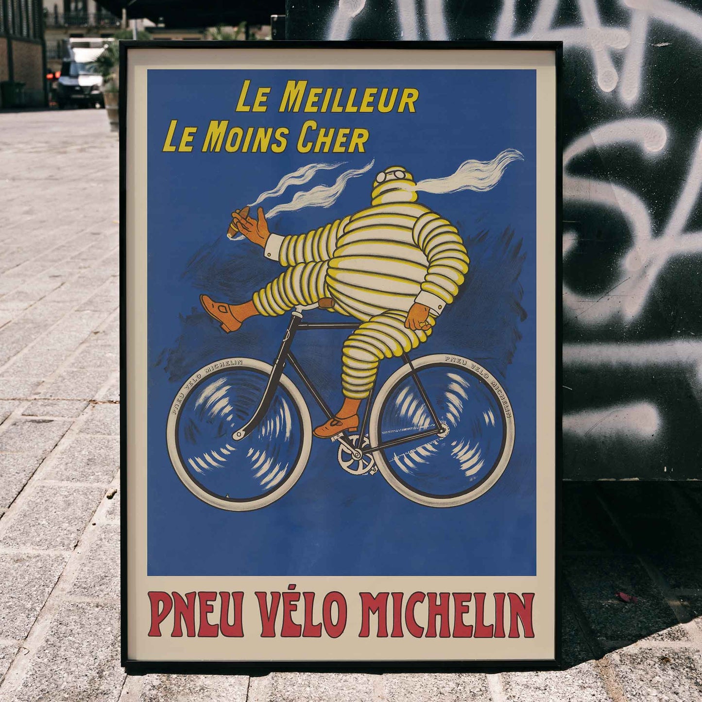 Marius Rossillon Michelin bicycle tire poster with striped cyclist riding bicycle on blue background with yellow text, framed and displayed in home decor