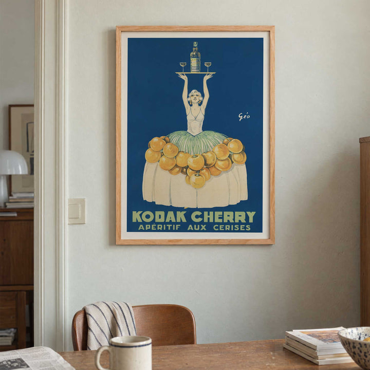 Géo Vermeire Kodak Cherry poster with woman in cherry-covered dress holding tray with bottle and two glasses, with wooden magnetic frame on white background