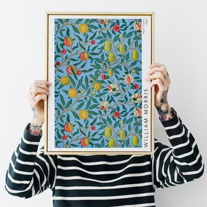 Colorful botanical wallpaper and poster featuring fruits and leaves from Four Fruits pattern by William Morris on blue background for wall decor, framed and displayed in home decor