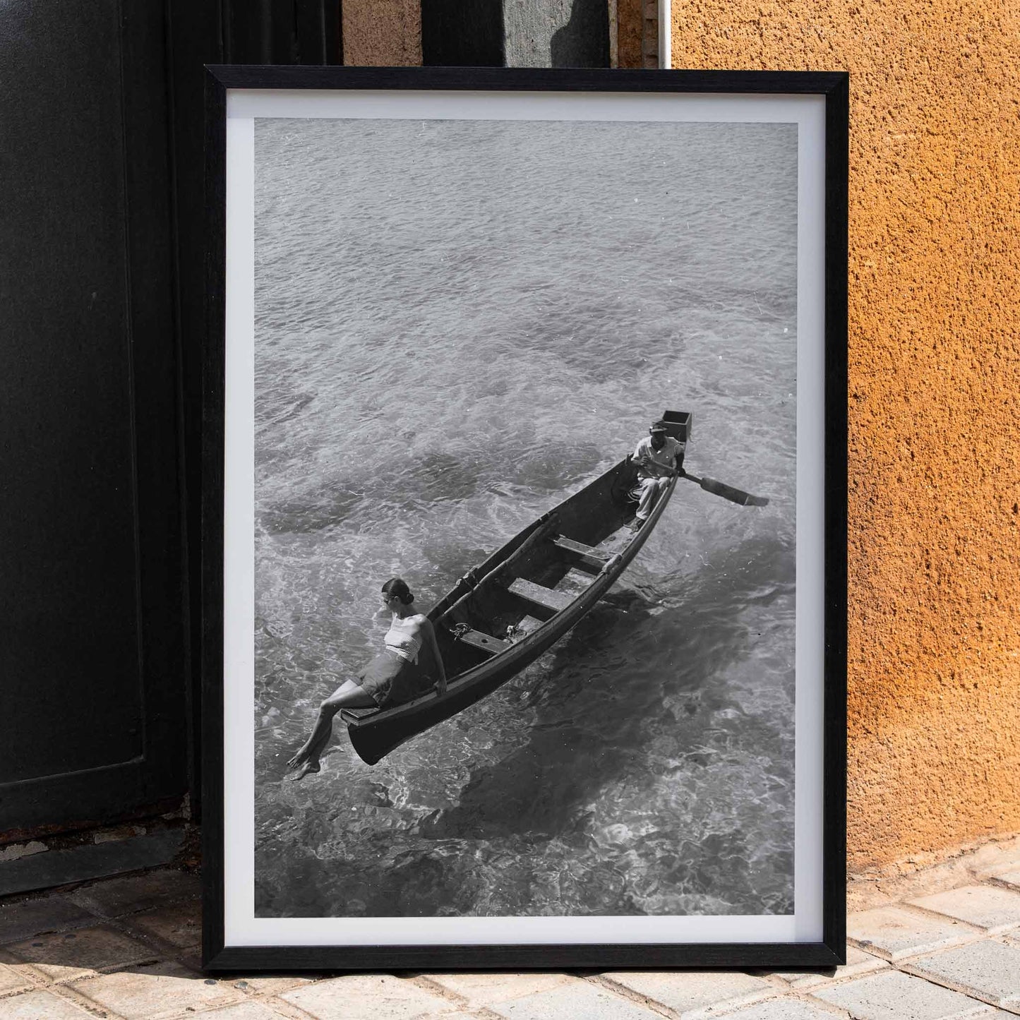 Fashion model on boat edge with man rowing in clear water Montego Bay Jamaica by Toni Frissell artwork poster, framed and displayed in home decor