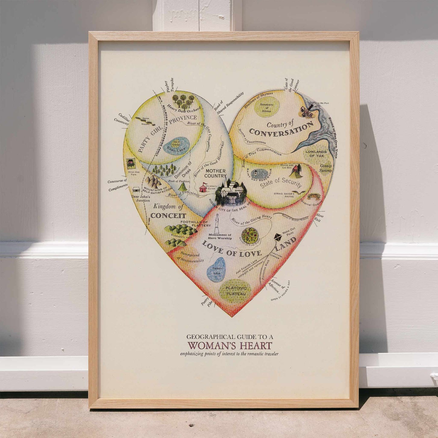 Heart shaped map illustration and poster Geographical Guide to a Womans Heart by Jo Lowery whimsical map of emotions in the shape of a heart, framed and displayed in home decor