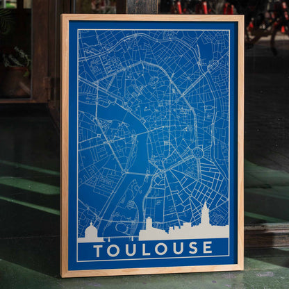 Blue and white minimalist map of Toulouse poster with white building silhouettes at the bottom modern wall art titled Minimalist Toulouse Map, framed and displayed in home decor