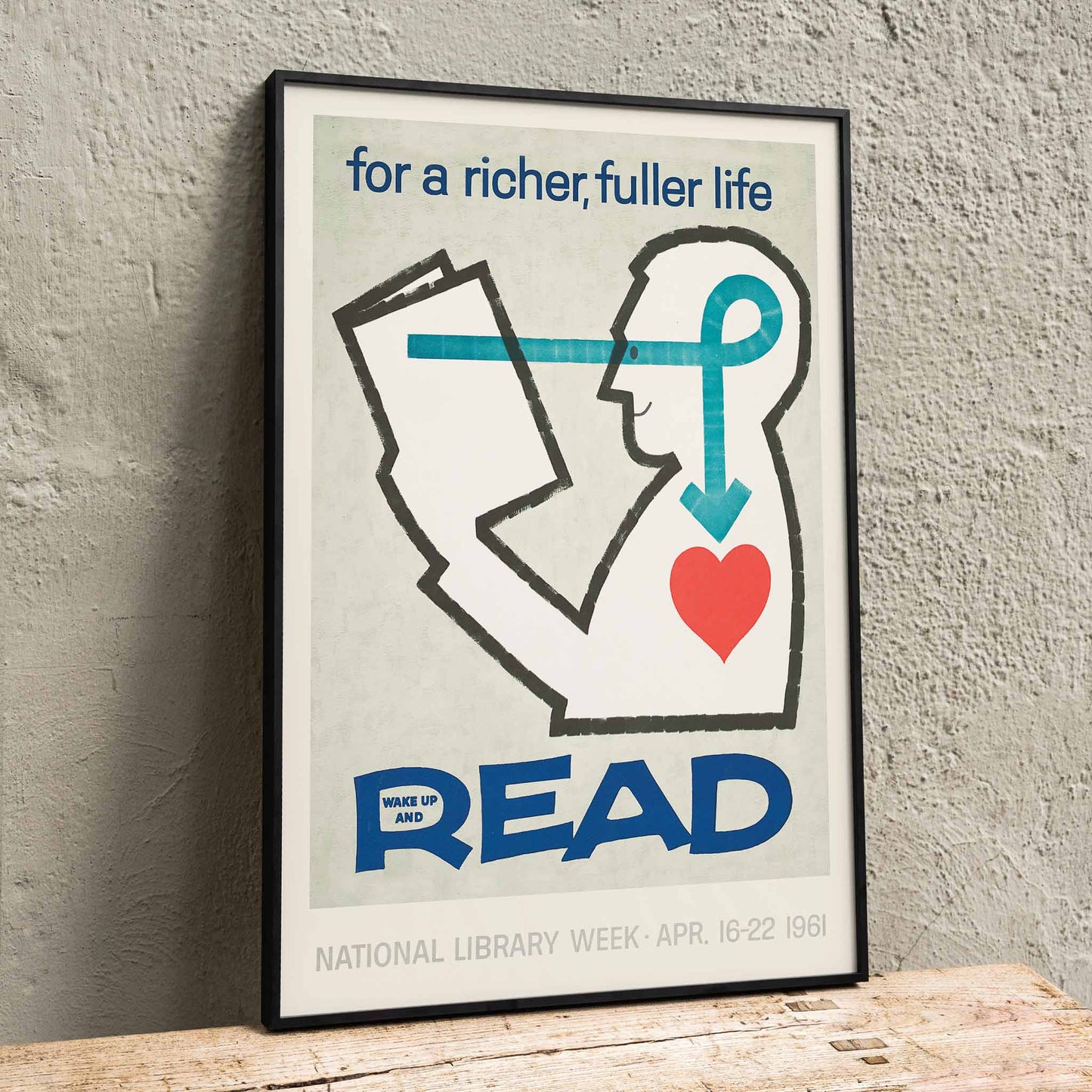 Poster with a stylized person reading a book and heart with bold text for a richer fuller life wake up and read by National Library, framed and displayed in home decor