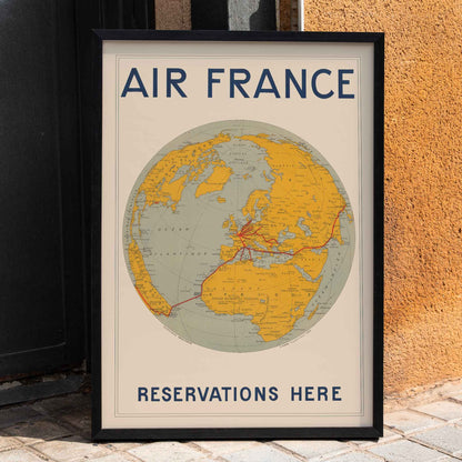 Vintage Air France travel poster by E Giraud showing world map with airline routes highlighted in red, framed and displayed in home decor