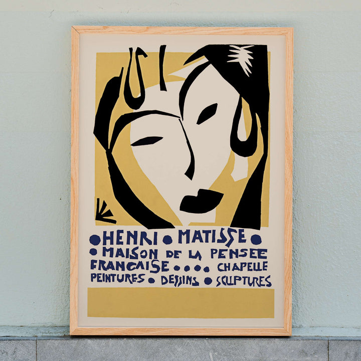 Henri Matisse Maison de la Pensee francaise poster with bold black abstract face shapes on warm yellow and cream minimalist design, framed and displayed in home decor