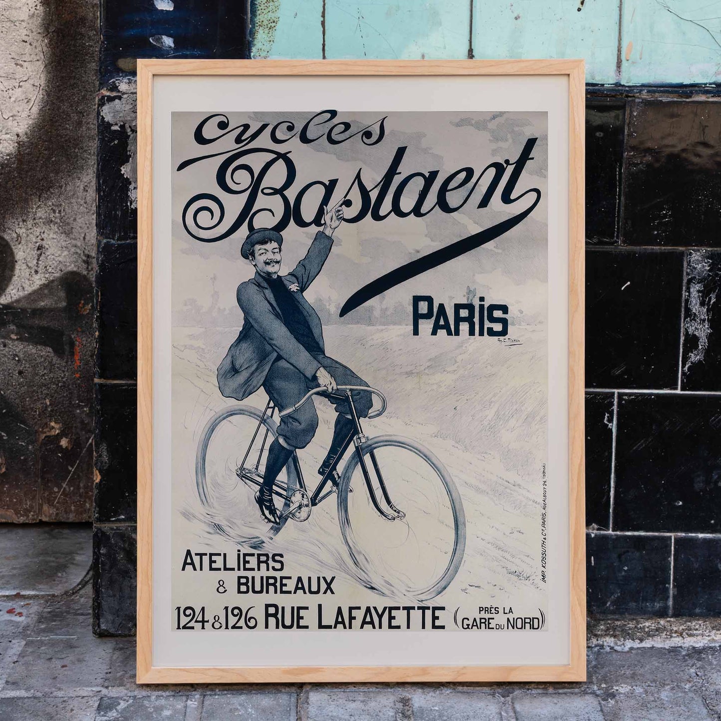 Vintage bicycle poster joyful man riding and waving on Cycles Bastaent Paris bike artwork by Charles Tichon, framed and displayed in home decor