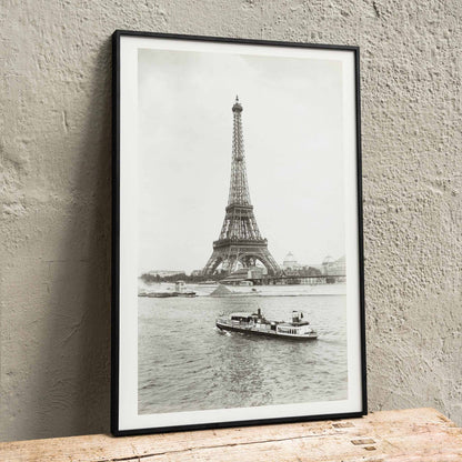 Black and white photograph and poster of the Eiffel Tower in Paris with a vintage boat on the Seine river wall decor artwork, framed and displayed in home decor