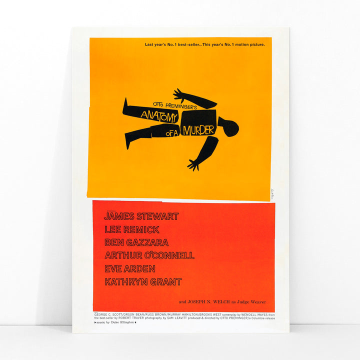 Movie poster of Anatomy of a Murder by Saul Bass features a yellow and red design with a black silhouette of a body, framed and displayed in modern living room decor
