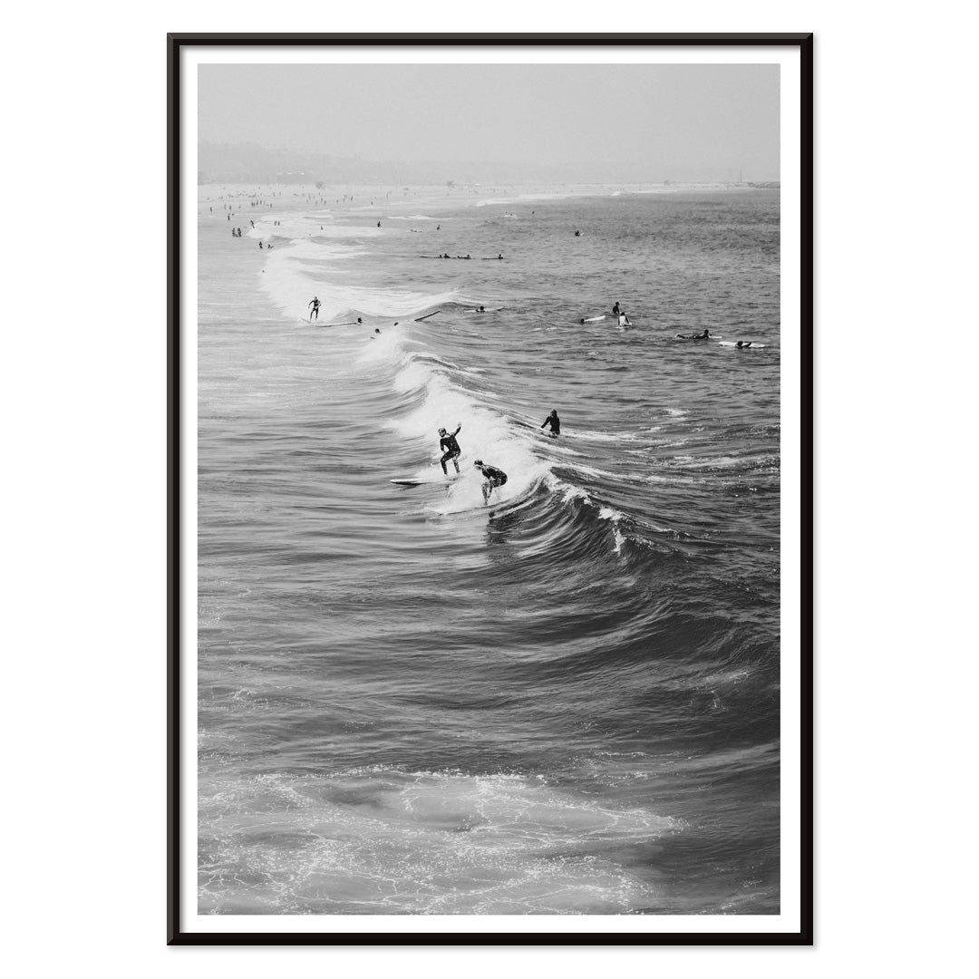Black and white surfers riding waves at Venice Beach coastal wall art poster ideal for home decor, with black aluminium frame on white background